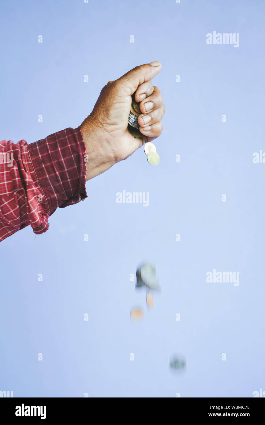 Cropped Image Of Hand Dropping Coins Against Purple Background Stock Photo