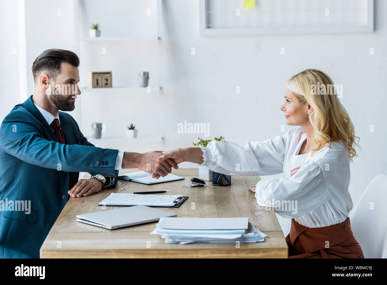 selective focus of handsome recruiter and attractive employee shaking hands Stock Photo