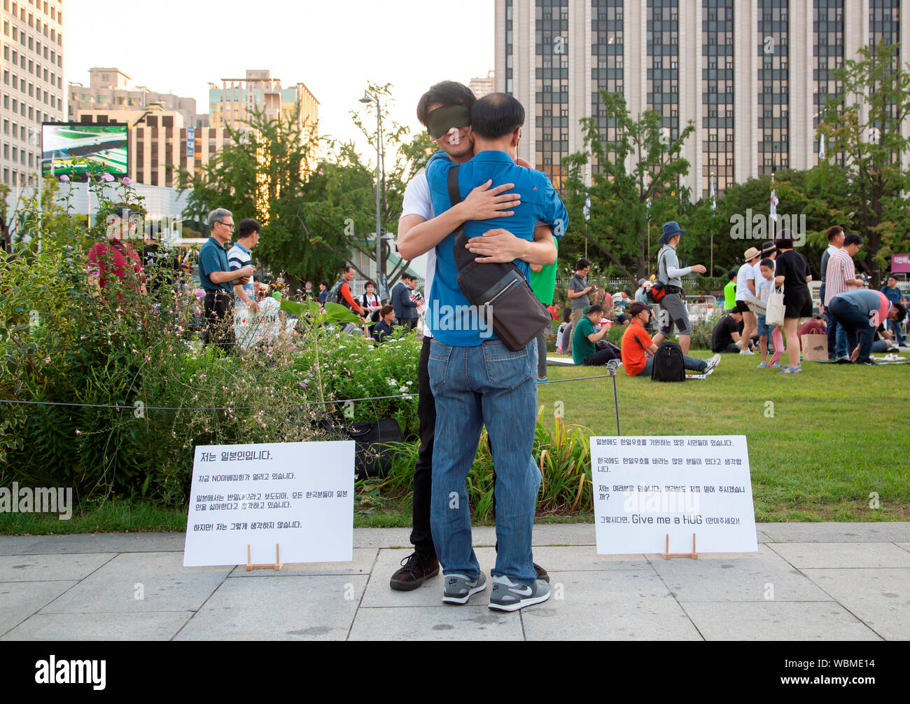Koichi Kuwabara, August 24, 2019 : Japanese Koichi Kuwabara (back) gives a free hug to a South Korean man during a Free Hugs campaign in his hopes of friendly relations between Japanese people and South Korean people at Gwanghwamun Square, a venue where a rally to denounce Japanese Prime Minister Shinzo Abe and his regime was being held in Seoul, South Korea. Hundreds of people attended the rally. South Korea's General Security of Military Information Agreement (GSOMIA) with Japan is set to expire on November 23, 2019 as Seoul decided on August 23 not to extend GSOMIA amid a trade spat with Ja Stock Photo