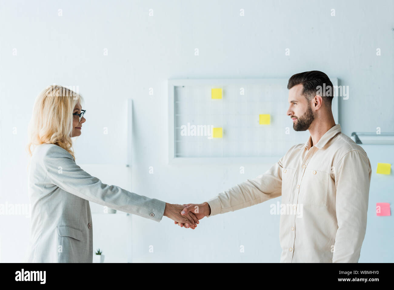attractive recruiter in glasses and handsome employee shaking hands Stock Photo