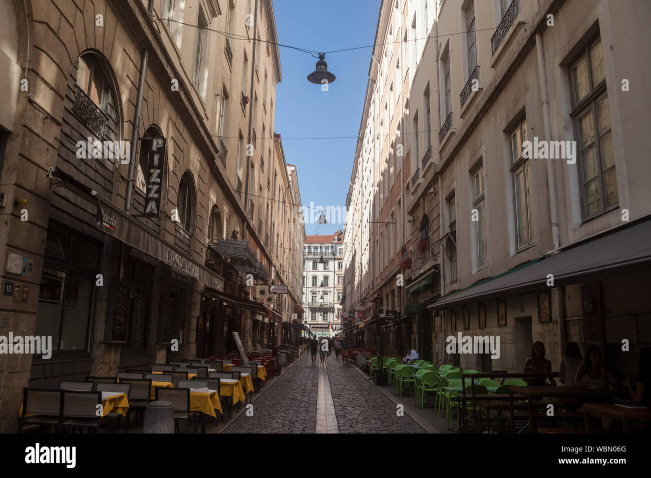 LYON, FRANCE - JULY 19, 2019: Typical narrow street of the Vieux Lyon (old Lyon) on the Presqu'ile district with tourists passing by near restaurants Stock Photo