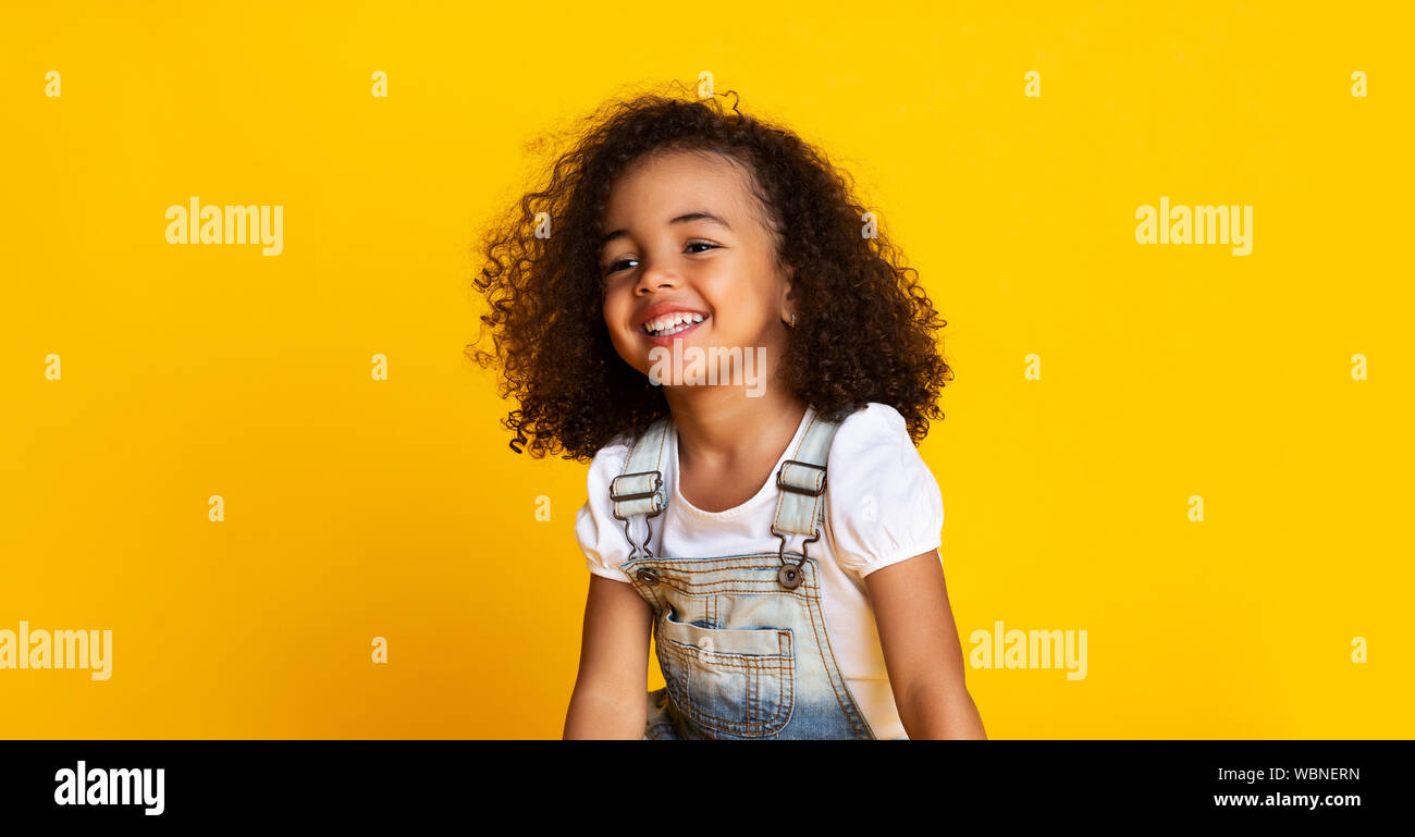 Laughing cute afro girl portrait, yellow background Stock Photo