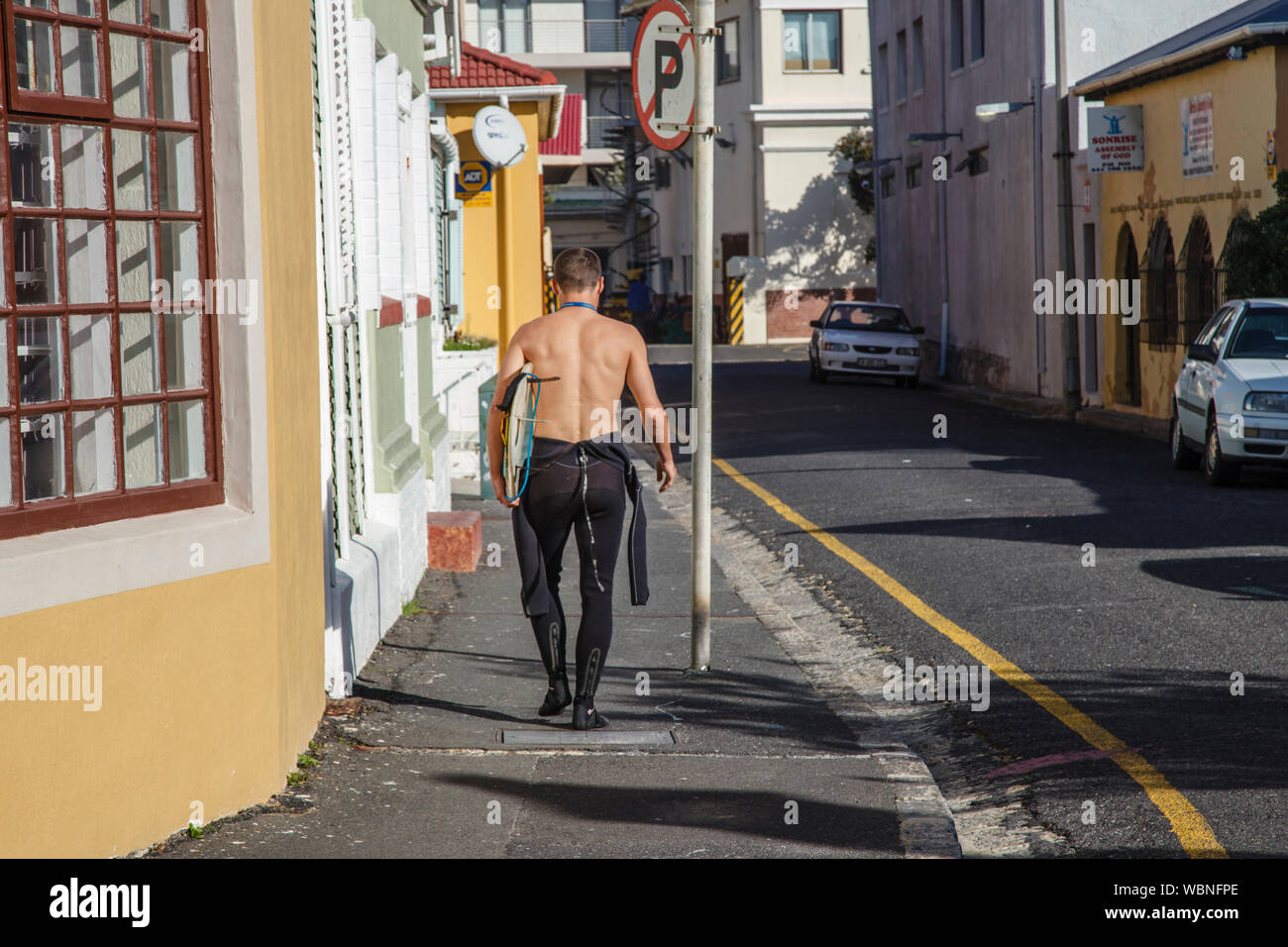 Surfer walking through the streets of Muizenberg, South Africa Stock Photo