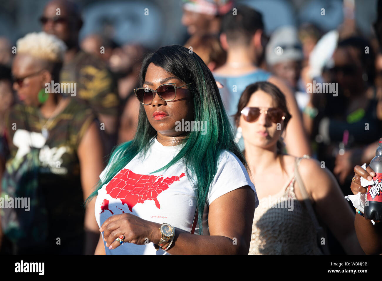 A woman with green hair and sunglasses attending Notting Hill Carnival, the largest carnival in Europe. Stock Photo