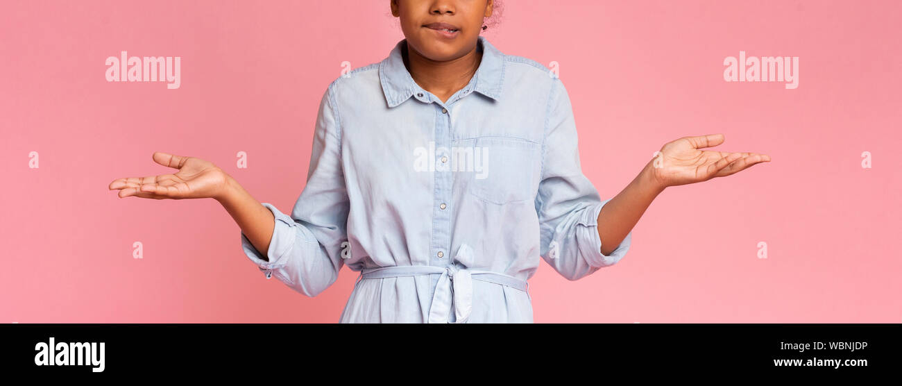 Confused black teen girl biting lip and shrugging shoulders Stock Photo