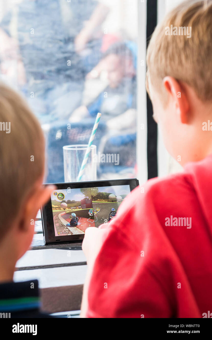 Two young boys engrossed in playing a game on a Nintendo Switch. Stock Photo