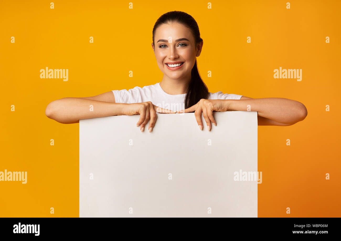 Smiling Girl Holding Empty White Board On Yellow Studio Background ...