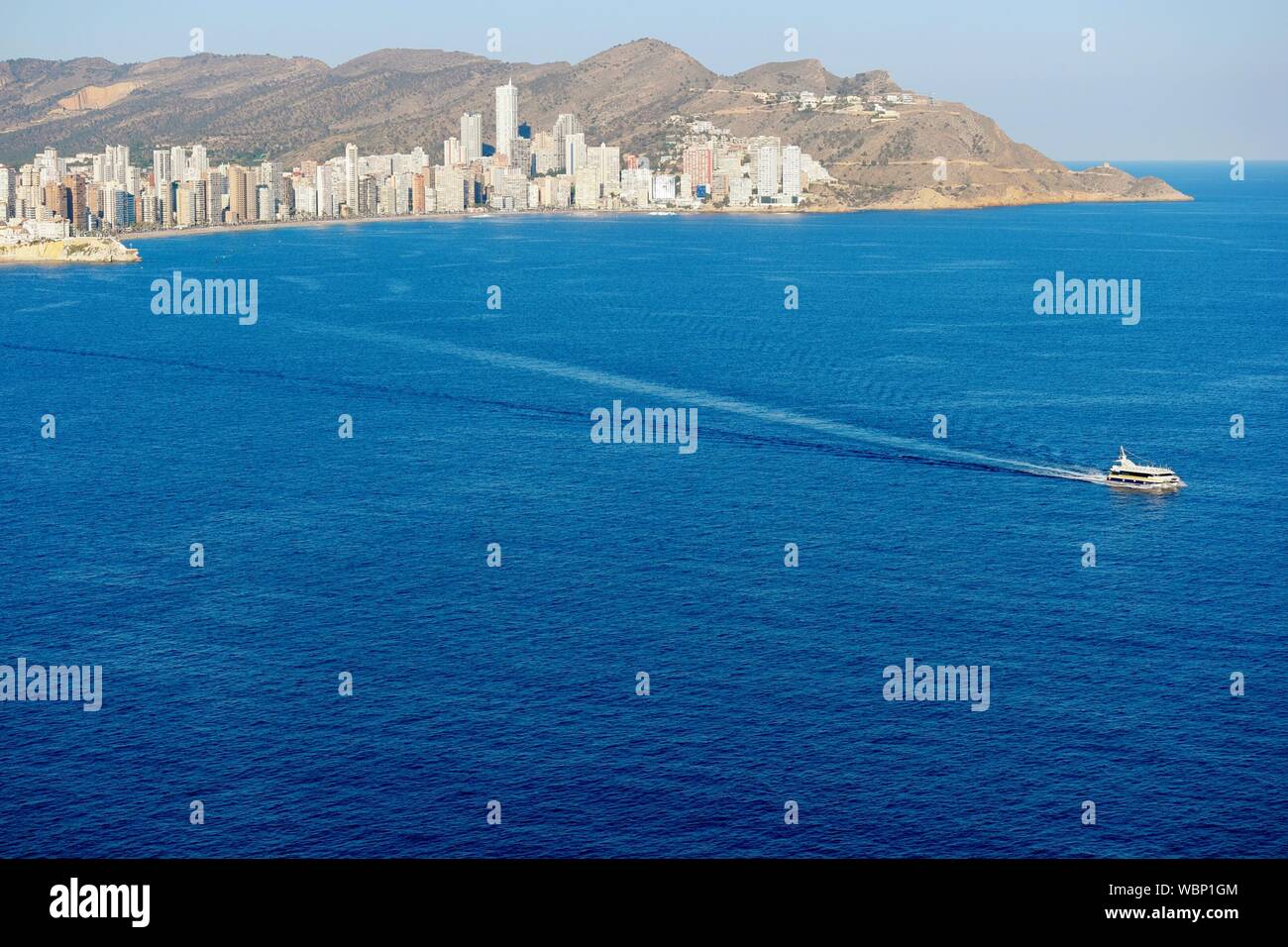 Boat In Sea With City And Hills In Background Stock Photo