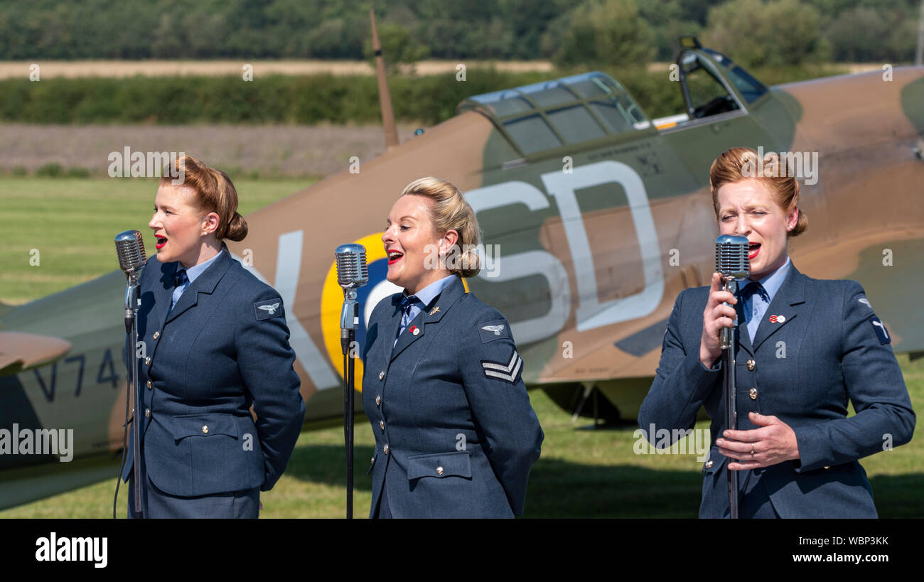 D-Day Darlings performing at the Children in Need Little Gransden Air and Car Show with a Hawker Hurricane Second World War fighter plane as backdrop Stock Photo