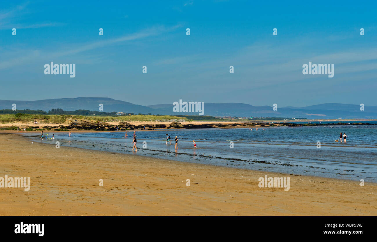 DORNOCH SUTHERLAND SCOTLAND PEOPLE IN THE SEA AND ON THE SANDS OF DORNOCH BEACH IN SUMMER Stock Photo