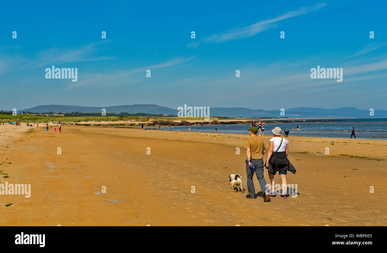 DORNOCH SUTHERLAND SCOTLAND PEOPLE IN THE SEA AND ON THE SANDS OF DORNOCH BEACH ON A DAY IN SUMMER Stock Photo