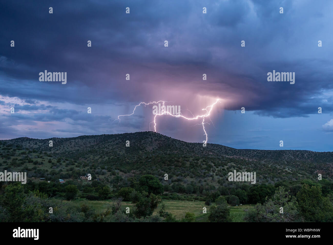 Lightning Strikes behind a hillside in the Mimbres Valley of New Mexico Stock Photo