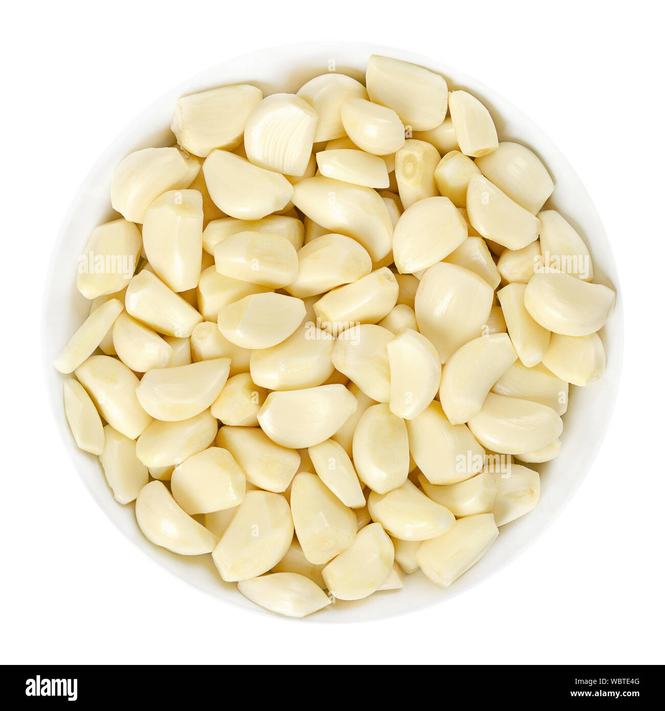 Peeled garlic cloves in white bowl, from above. Allium sativum, with pungent flavor, used as seasoning or condiment and in medicine. Stock Photo