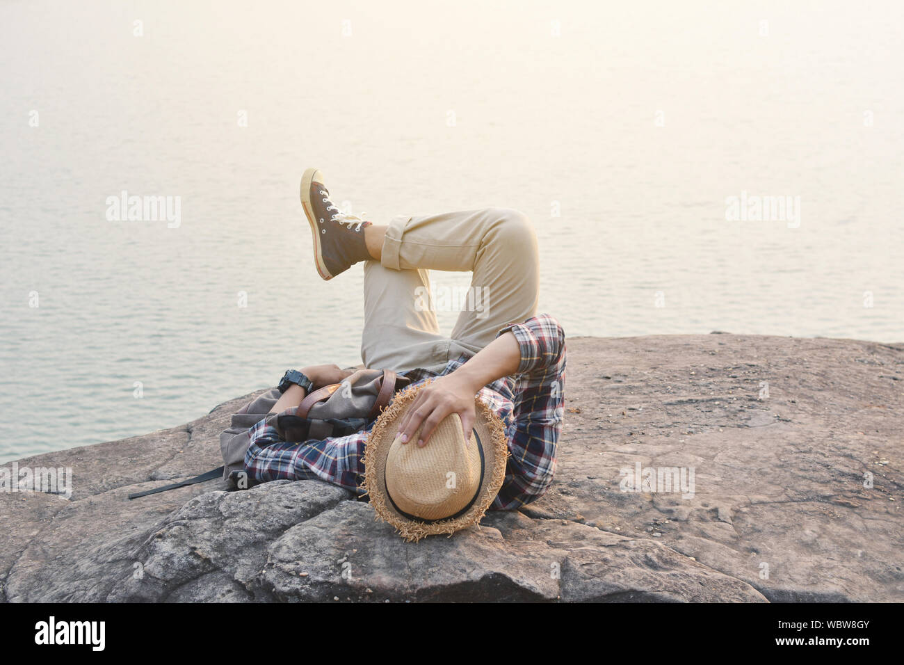 Man Relaxing On Rock Against River During Foggy Weather Stock Photo
