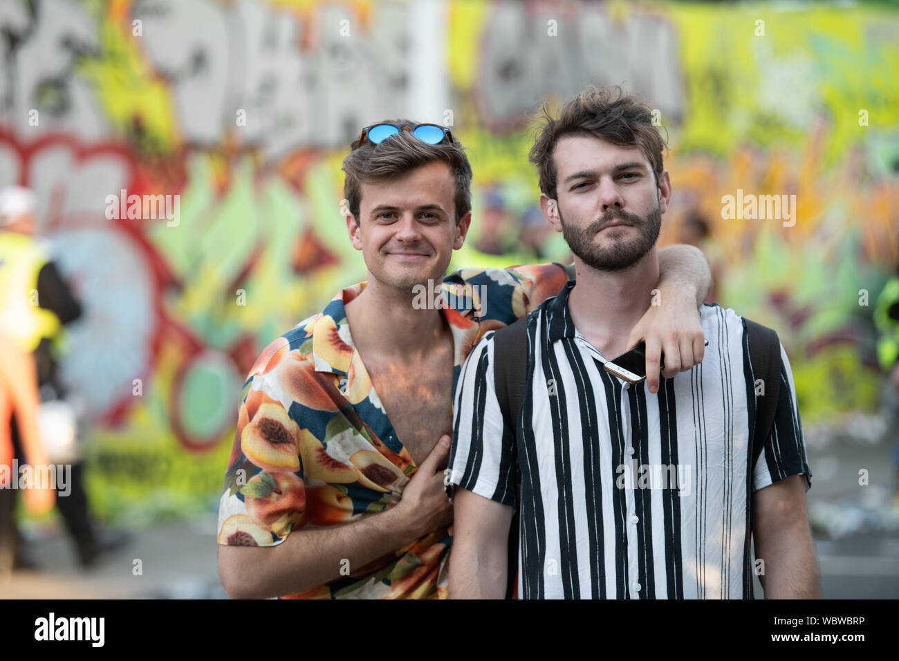 Two Caucasian men standing text to each other wearing colourful shirts smiling at Notting Hill Carnival. Stock Photo