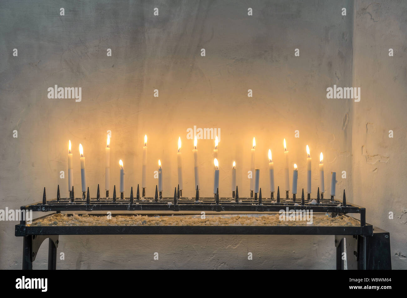 Eighteen burning white candles on a black framework in an interior