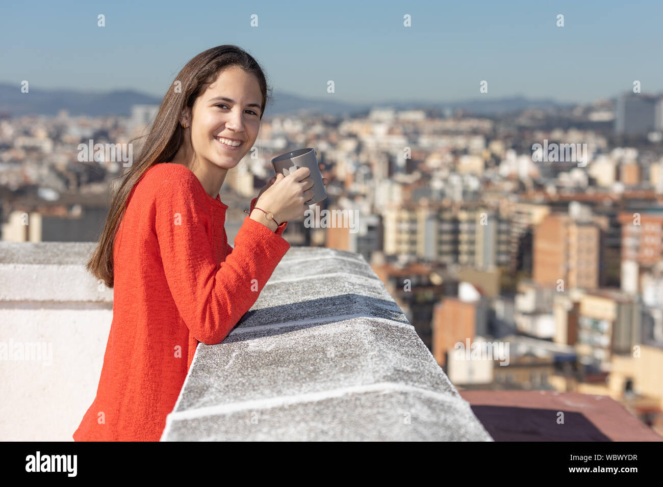 Adolescente en la terraza tomando una taza de te sonriendo Stock Photo