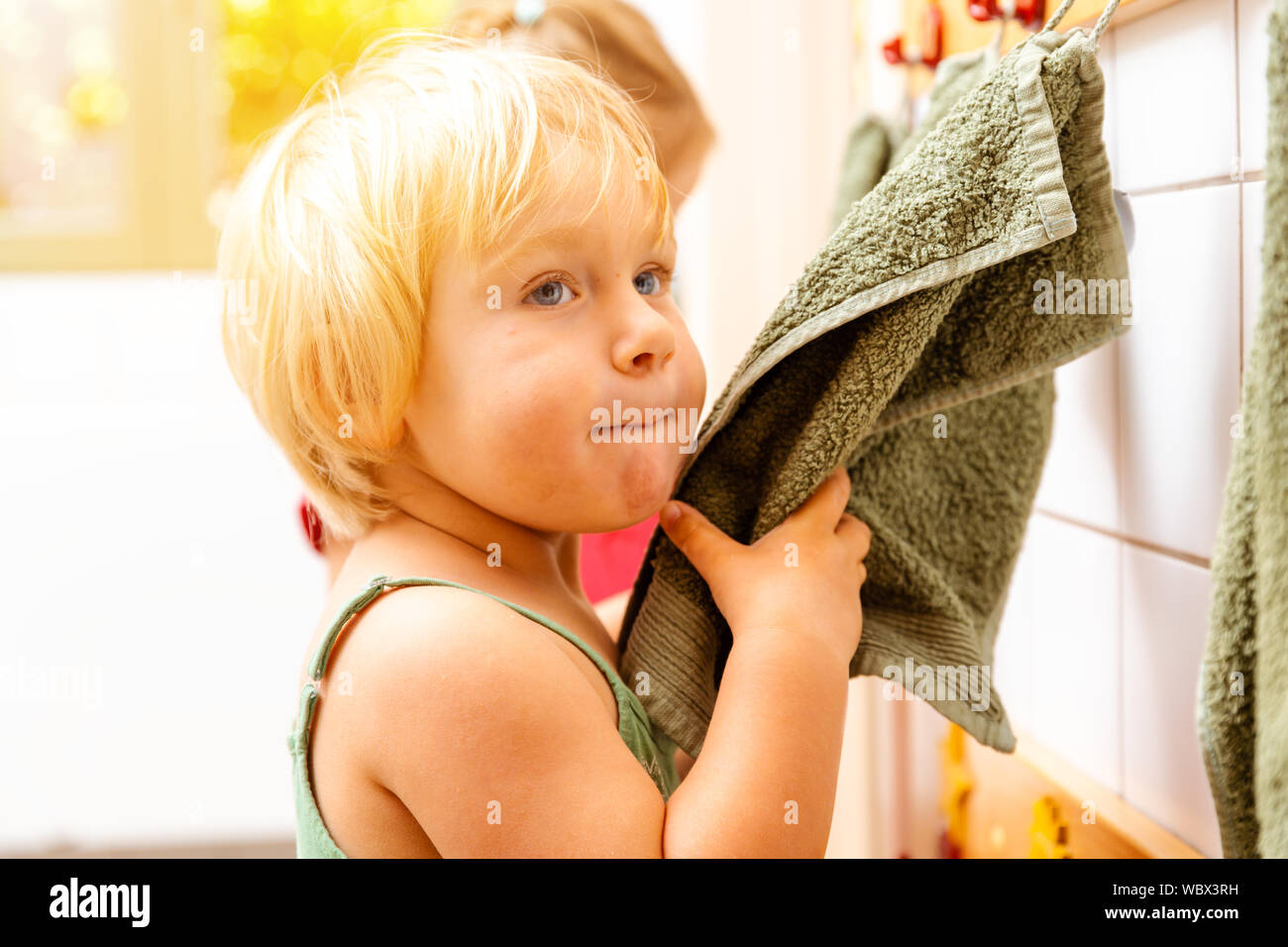 Little girl in nursery school using towel in bathroom Stock Photo