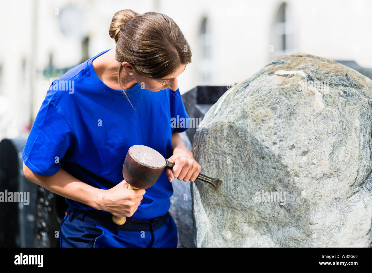 Stonemason working on boulder with sledgehammer and iron Stock Photo Alamy