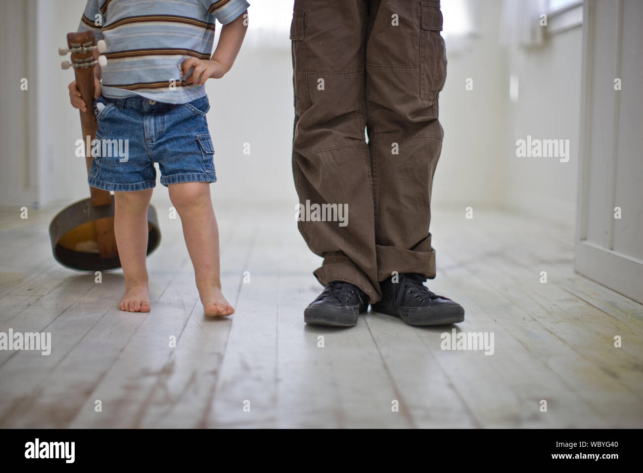 Little boy holding banjo and his older brother standing in corridor Stock Photo