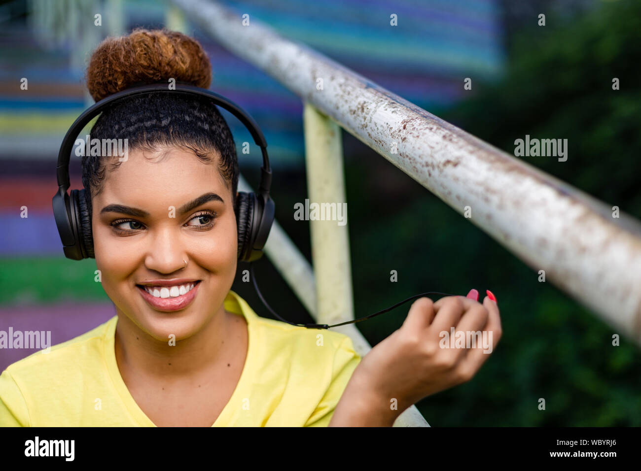 Pretty young black african american woman listening to music with a headphone outdoor Stock Photo