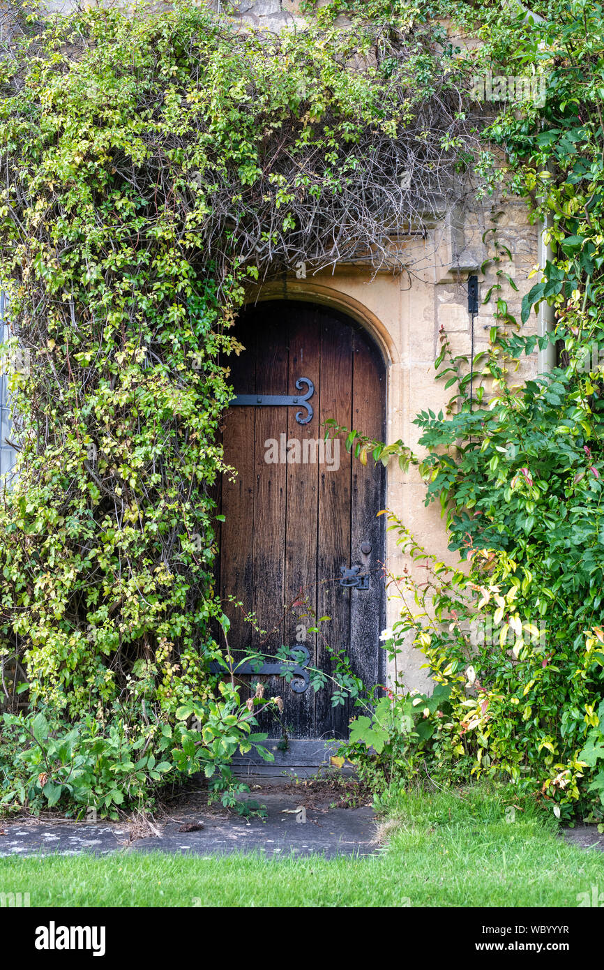 Cotswold stone cottage door surrounded by a climbing plant in the village of Overbury, Cotswolds, Worcestershire, England Stock Photo