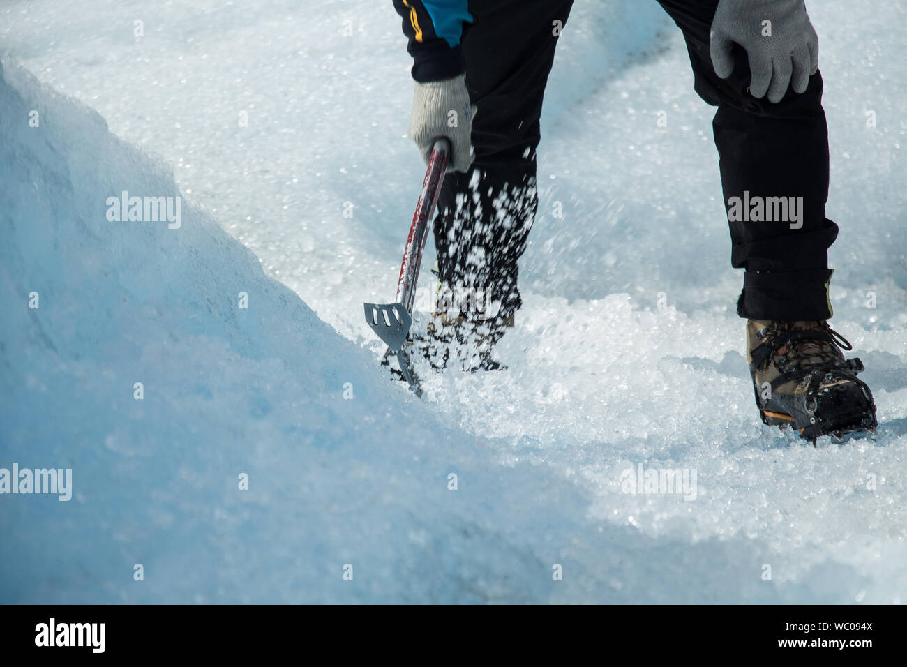 Low Section Of Man Striking Ice With Adze Stock Photo