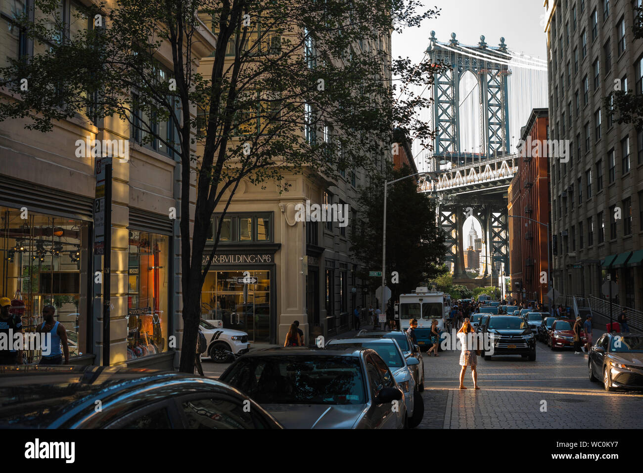 Dumbo New York, rear view of a woman taking a photo of the Manhattan Bridge in Washington Street in the Dumbo area of Brooklyn, New York City, USA. Stock Photo