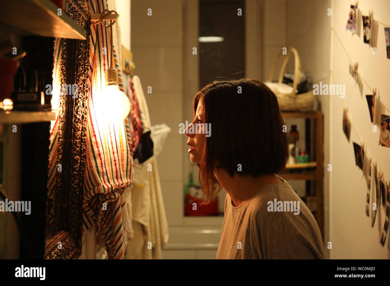 Side View Of Young Woman Looking Towards Illuminated Light Bulb At Home Stock Photo