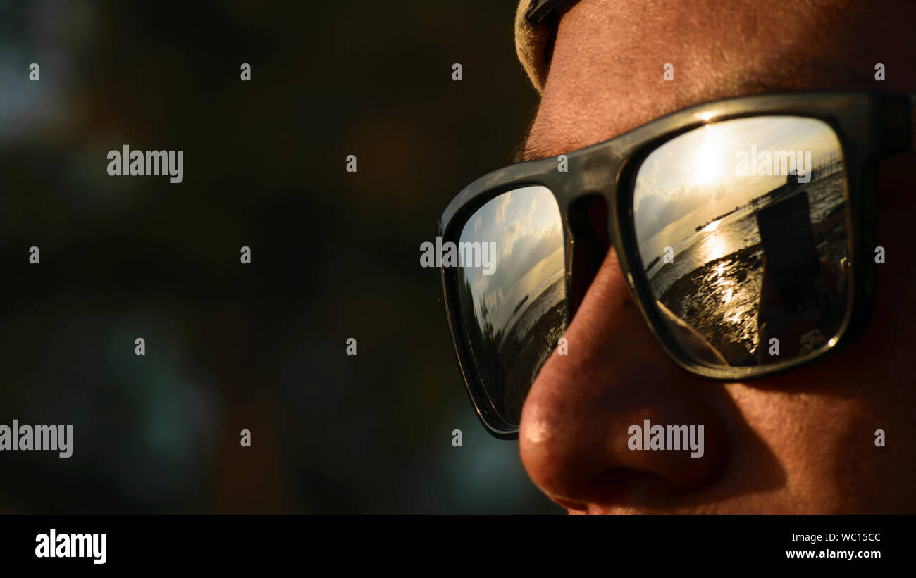 Cropped Image Of Man Wearing Sunglasses With Sea Reflection Stock Photo