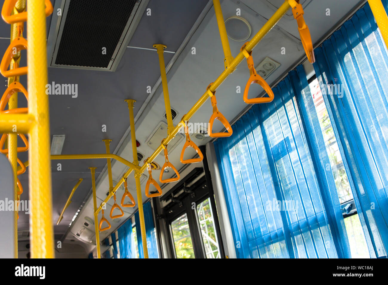 yellow  hanging handhold for standing passengers in a modern bus. Suburban and urban transport Stock Photo