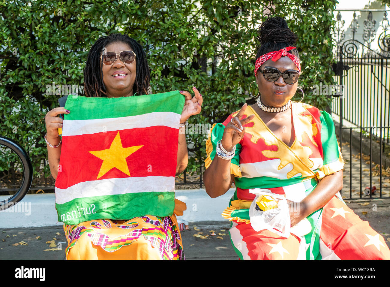 Happy confident lady spectators with a flag at the Notting Hill Carnival London. Stock Photo
