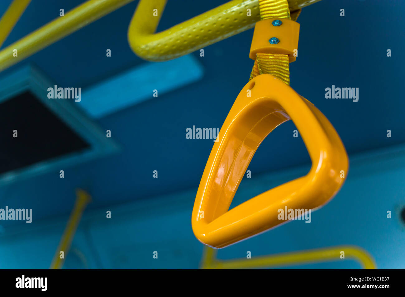 yellow  hanging handhold for standing passengers in a modern bus. Suburban and urban transport Stock Photo