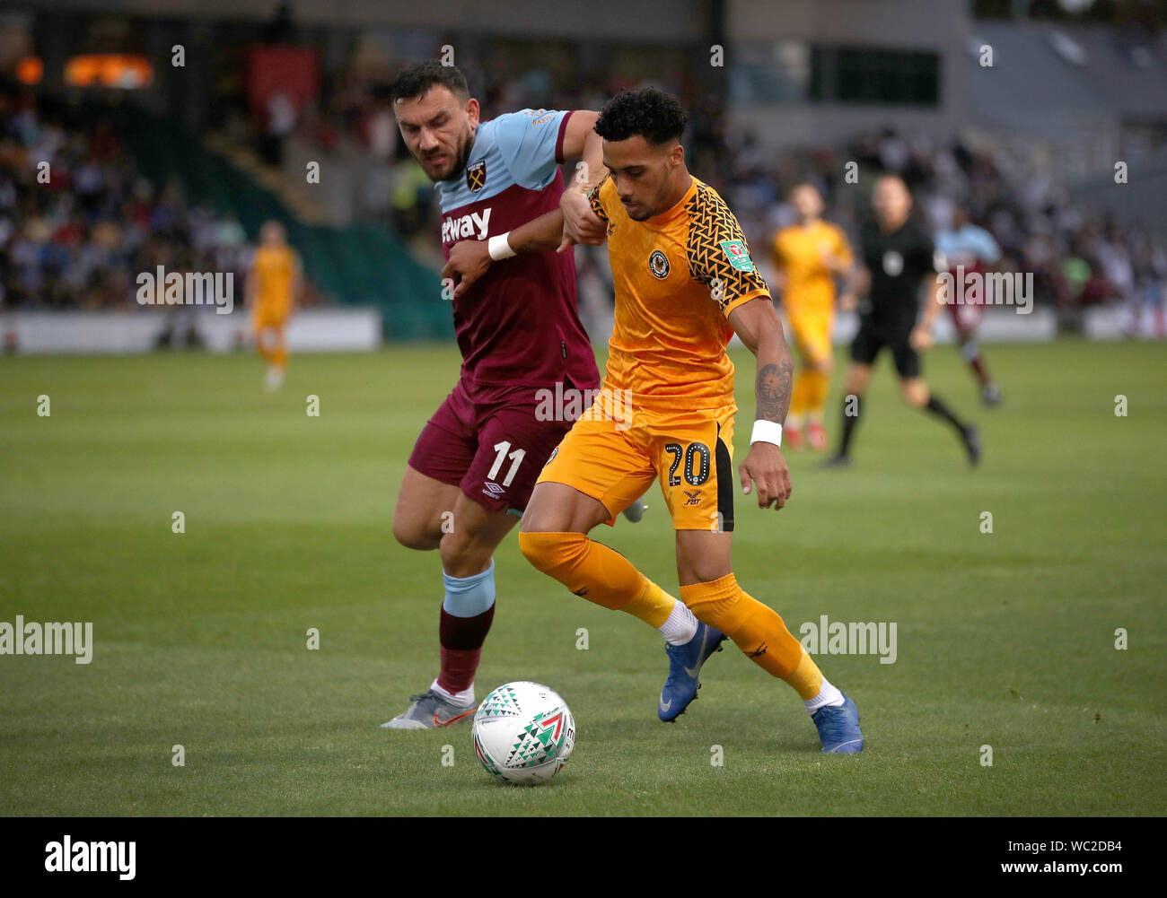 West Ham United's Robert Snodgrass (left) and Newport County's Corey Whitely battle for the ball during the Carabao Cup Second Round match at Rodney Parade, Newport. Stock Photo