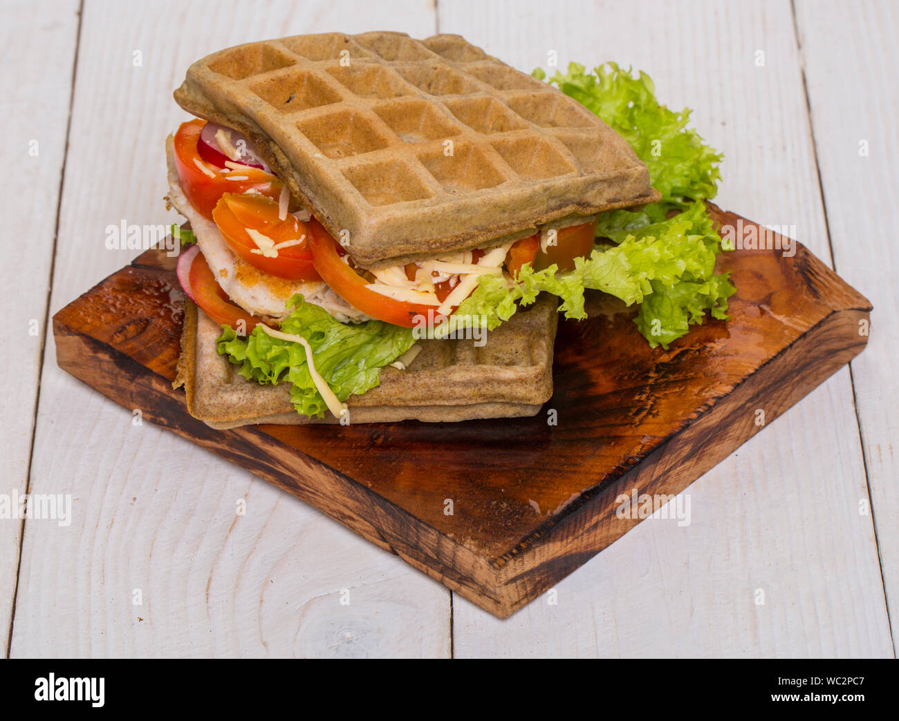 Waffles sandwich with chicken, vegetables and cheese on wooden background Stock Photo