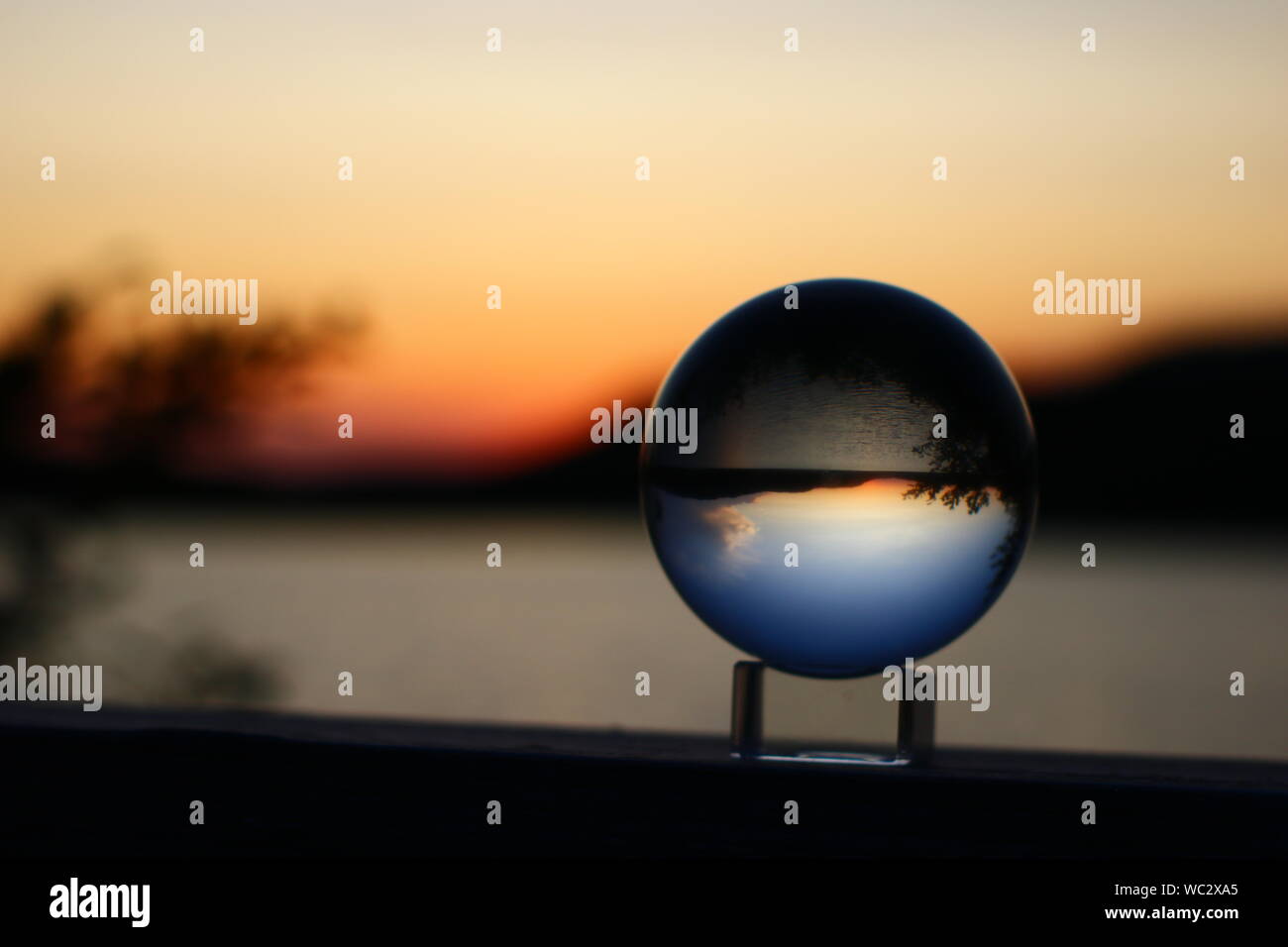Beautiful Sunset over a pond inside a Crystal Ball. (Background blurred ...