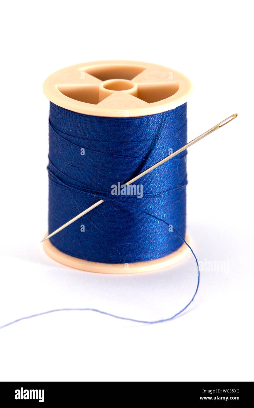 Single spool of blue thread and sewing needle on white background Stock