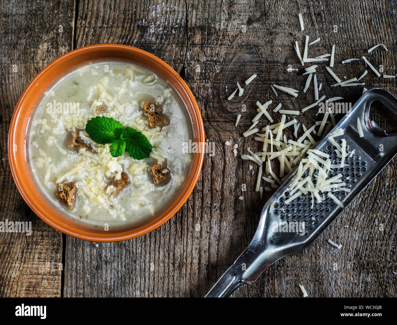 Directly Above Shot Of Vegetable Soup With Croutons And Grated Cheese On Wooden Table Stock Photo