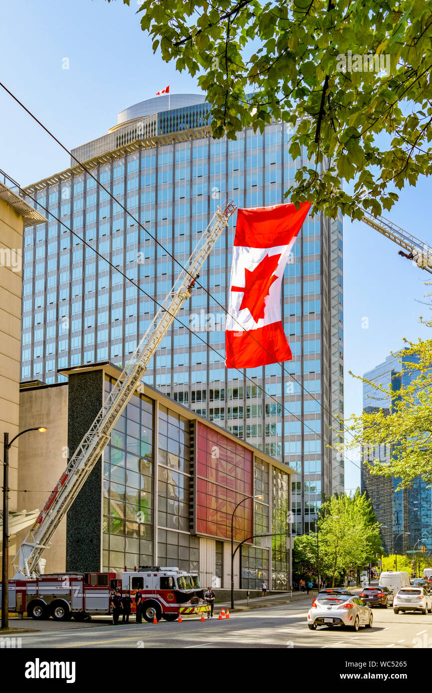 Canadian flag helsd aloft by 2 Fire truck ladders in salute to firefighter who died on duty, Vancouver, British Columbia, Canada Stock Photo