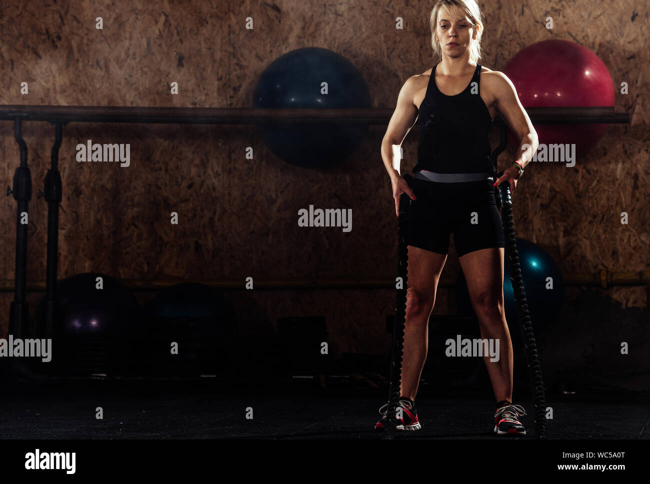 Female athlete making wave movement with battle rope during crossfit ...