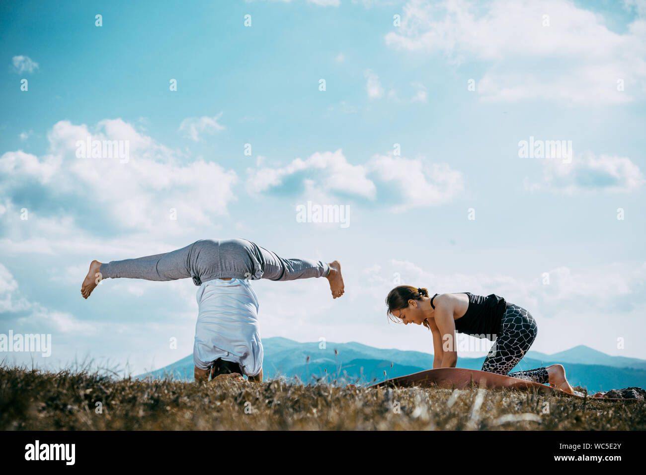 Strong and flexible young couple doing yoga workout. Man and woman on mountain practicing pair yoga in morning Stock Photo
