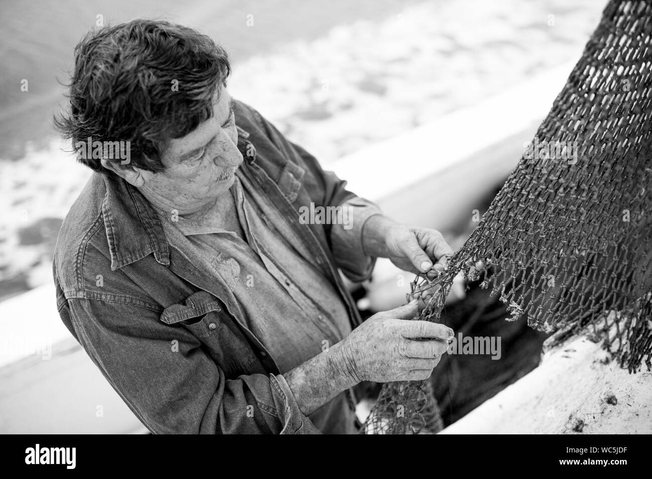 Commercial deckhand mending nets on fishing boat Stock Photo Alamy