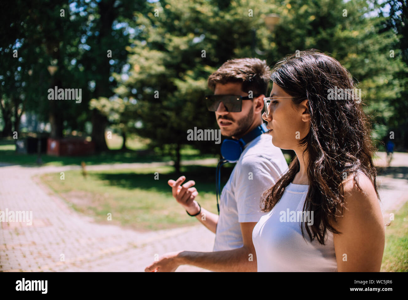 Couple talking seriously outdoors in a park with a green background Stock Photo