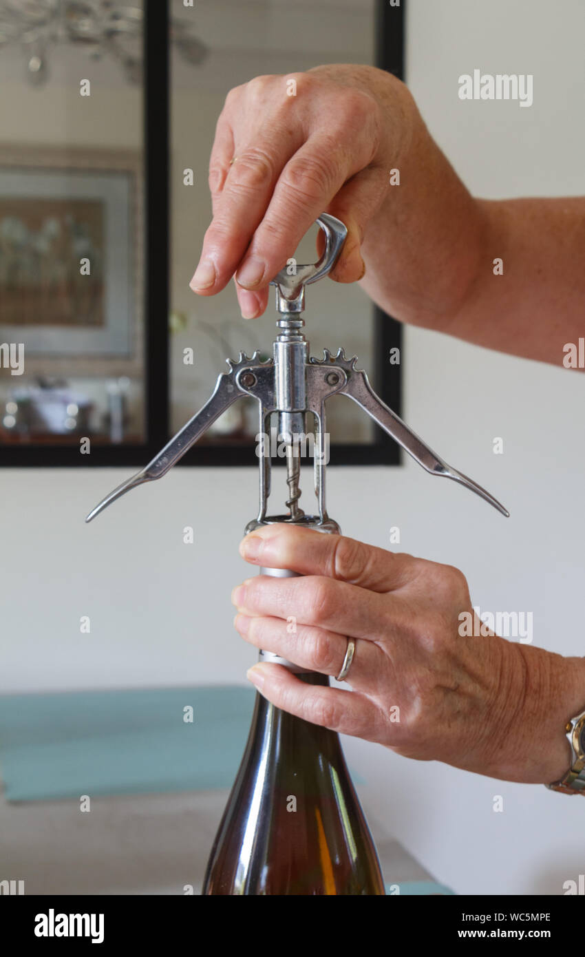 Hand of a woman opening a bottle of wine with a corkscrew Stock Photo