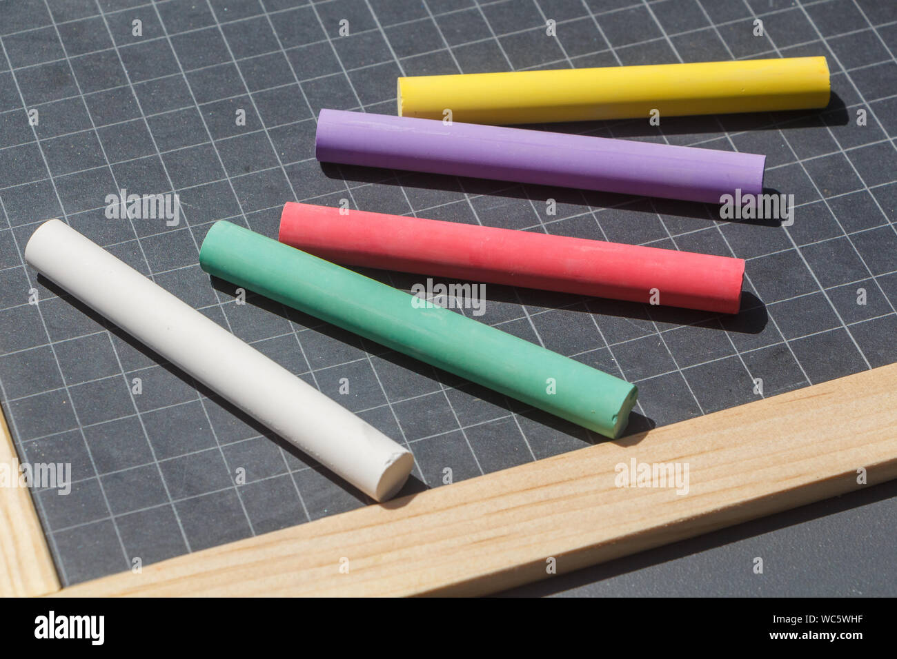 Squared chalkboard slate and five colored chalks Stock Photo Alamy