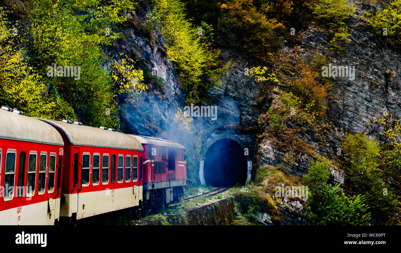 Wide View Of Train Entering Tunnel In Mountainous Landscape Stock Photo