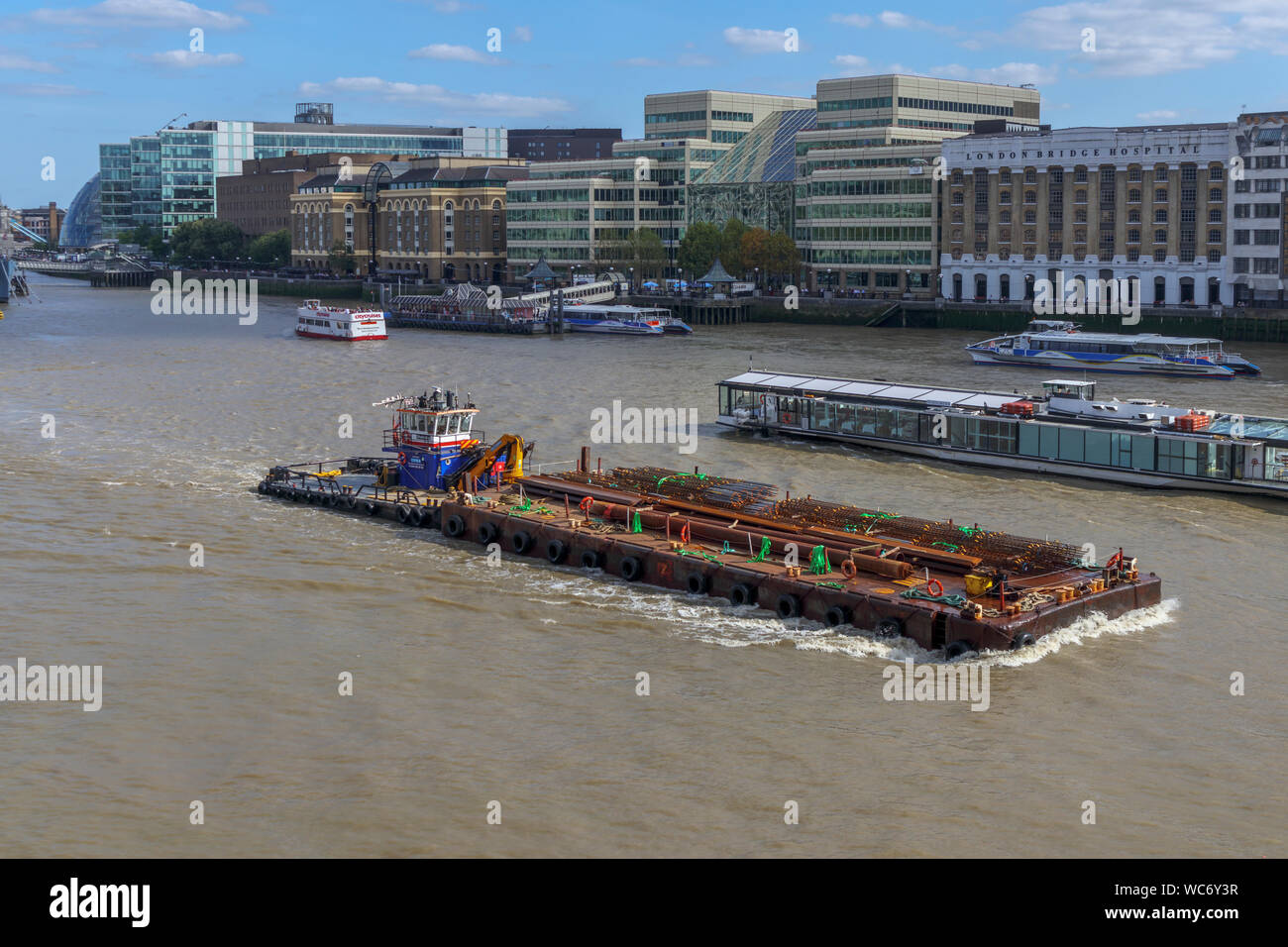 A large Multi-cat type workboat, MPV Shake Dog, delivers construction materials in the Pool of London, River Thames by Hays Galleria and London Bridge Stock Photo