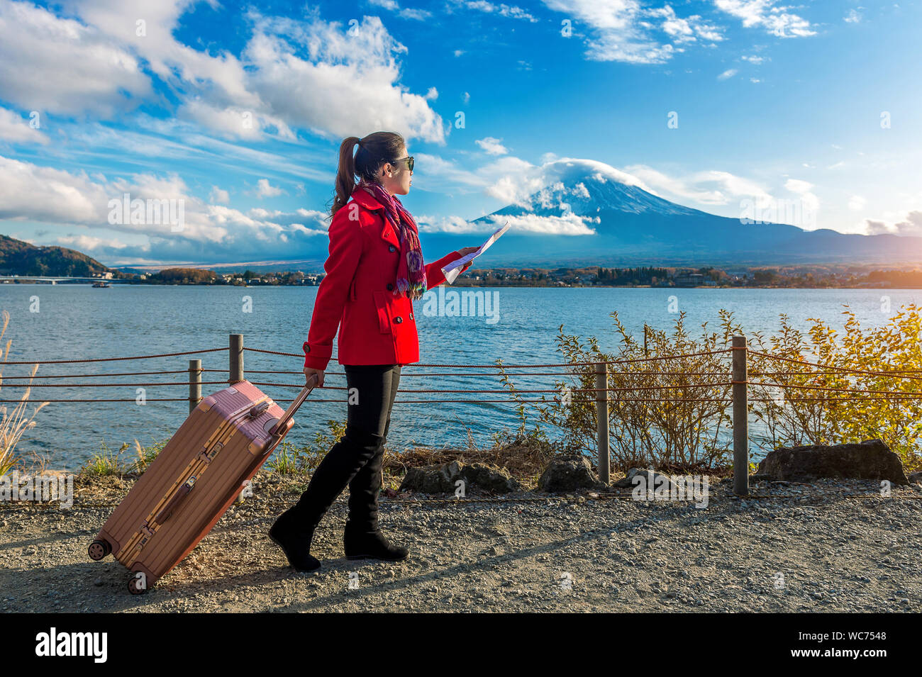 Full Length Of Woman With Luggage Standing By Lake Kawaguchi Holding Map Stock Photo