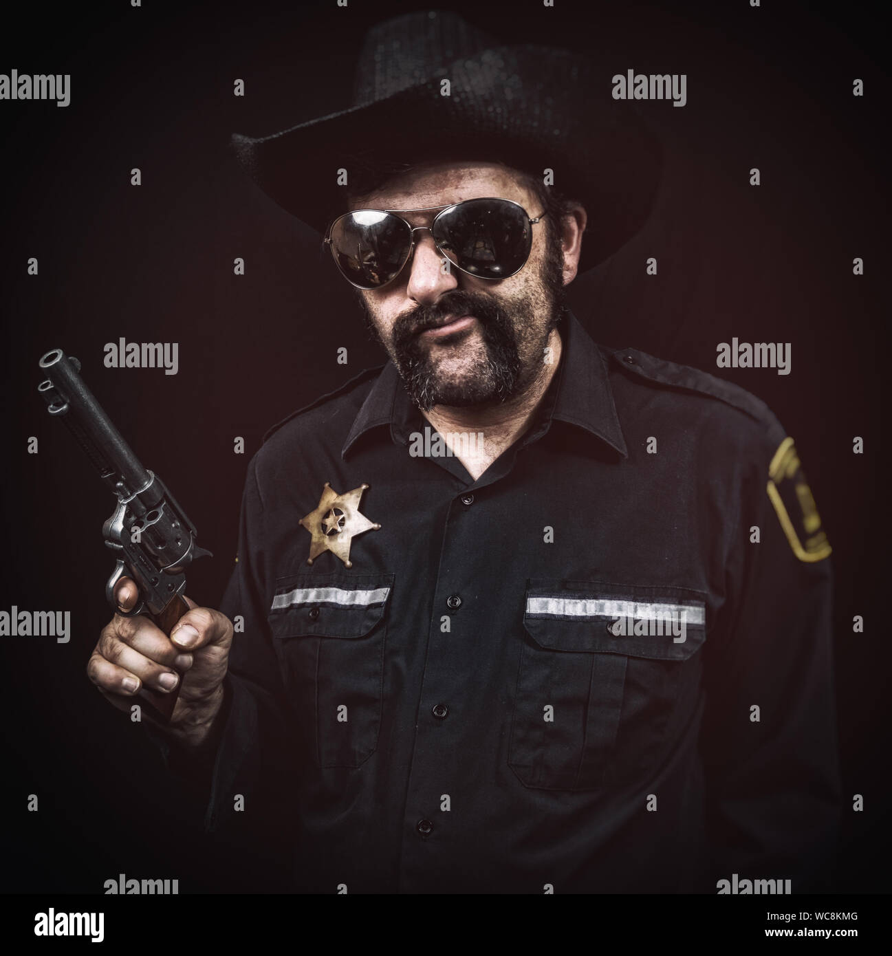 Sleazy southern style sheriff cop smirking or chewing tobacco with a greasy mustache, cowboy hat, and pistol. Stock Photo