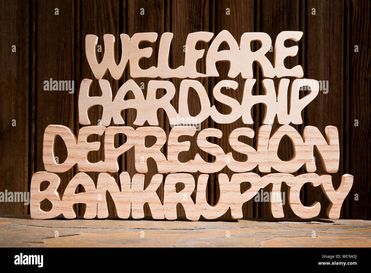 Words BANKRUPTCY, DEPRESSION, HARDSHIP, WELFARE-- hand cut from wood. Stock Photo